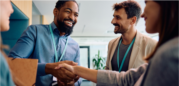 People shaking hands and smiling in a professional setting.
